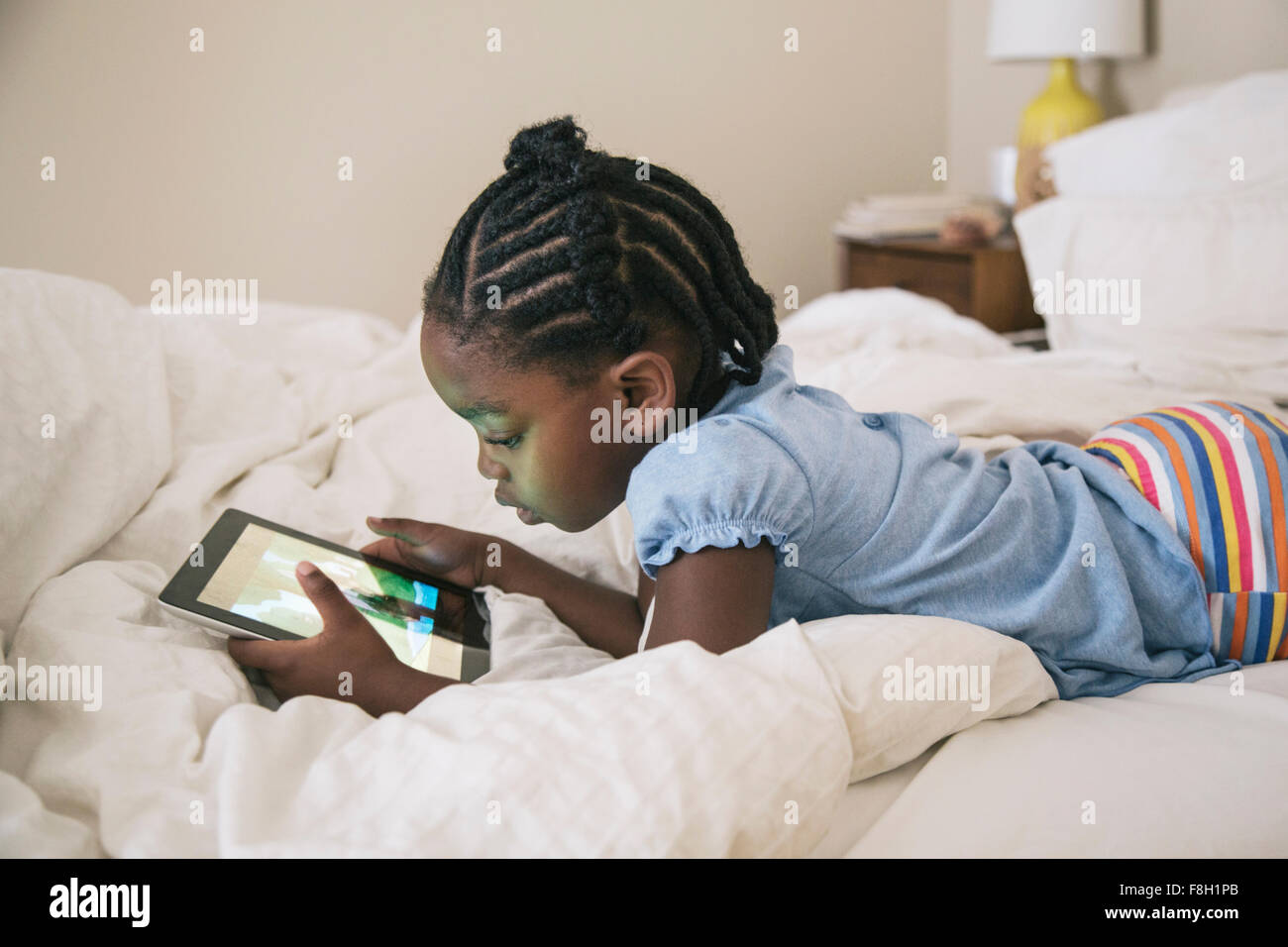 African American girl using digital tablet on bed Stock Photo