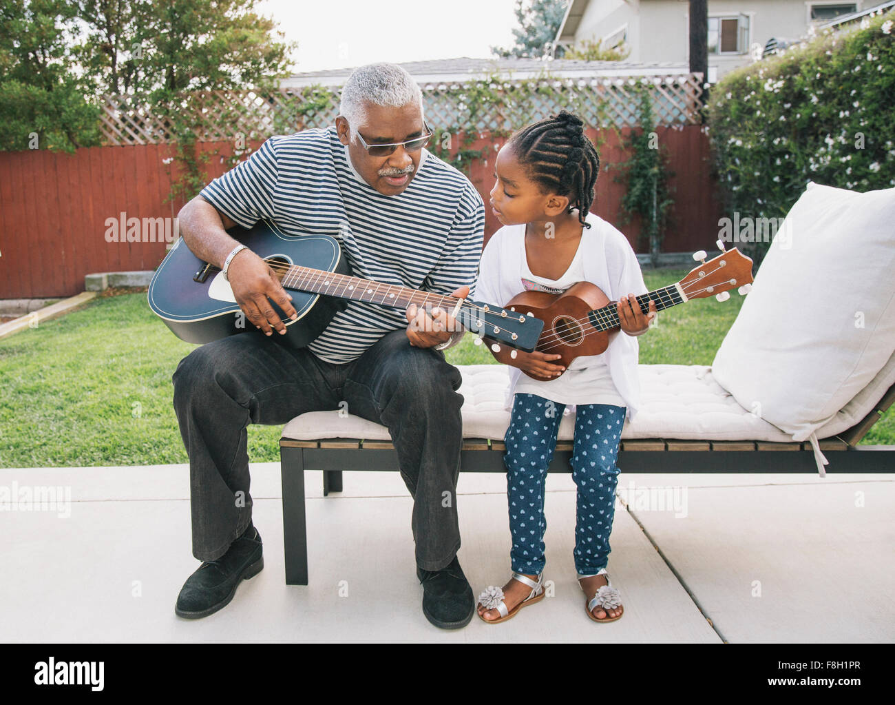 African American grandfather teaching granddaughter to play guitar Stock Photo