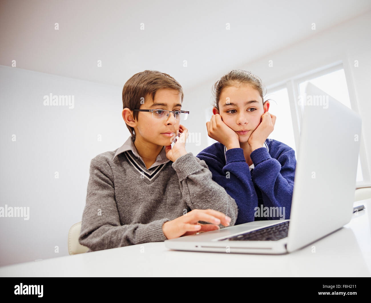 Mixed race children using laptop at desk Stock Photo