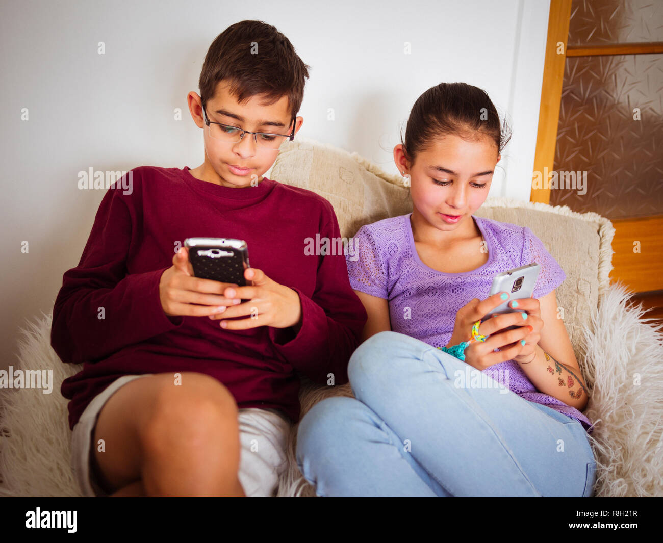 Mixed race children using cell phones Stock Photo