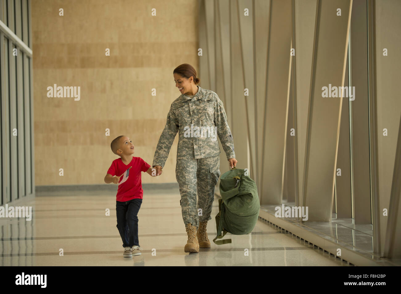 African American soldier and son walking in airport Stock Photo