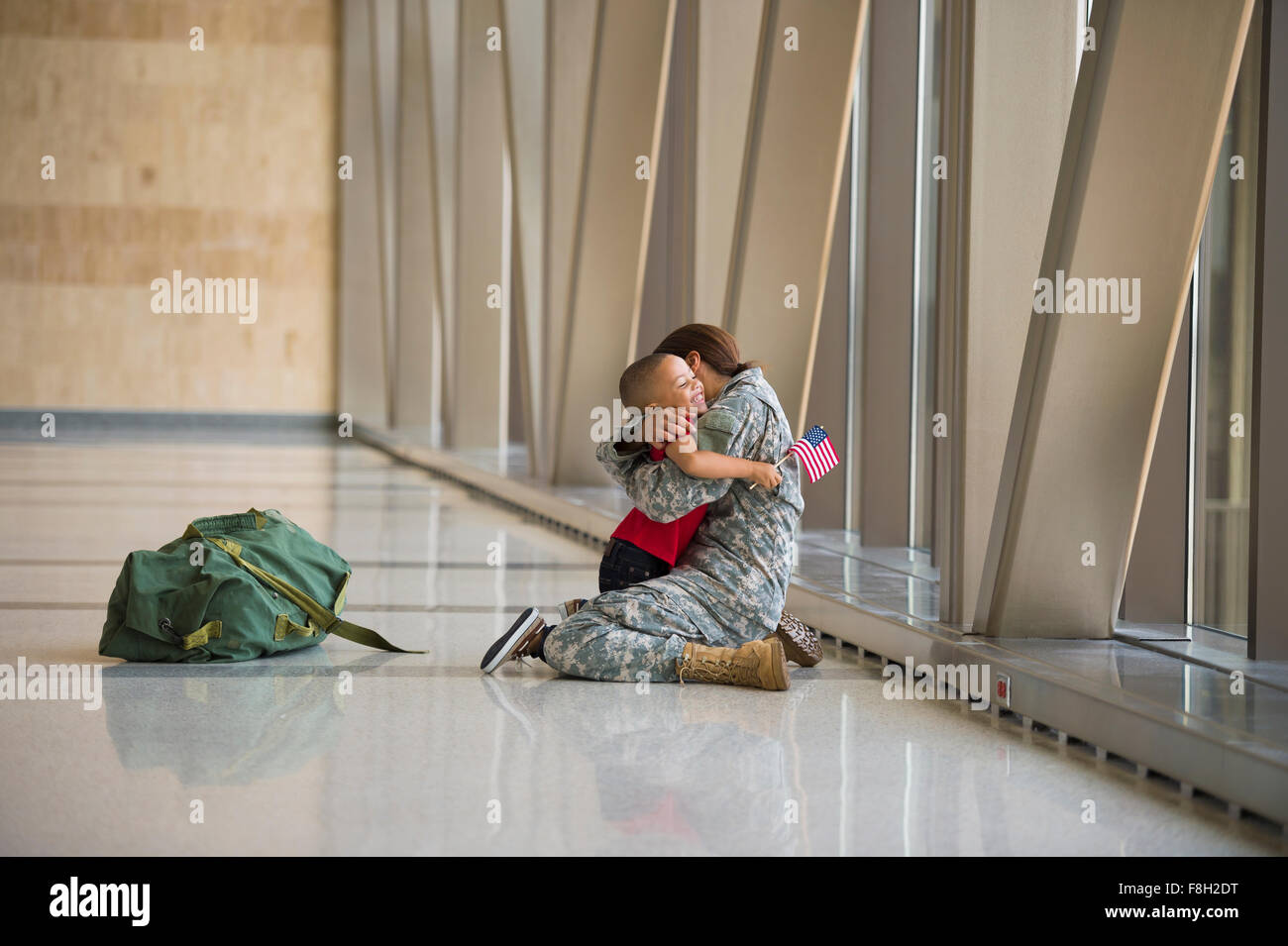 African American soldier hugging son in airport Stock Photo