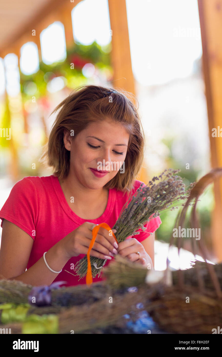 Mixed race girl tying bundle of flowers Stock Photo