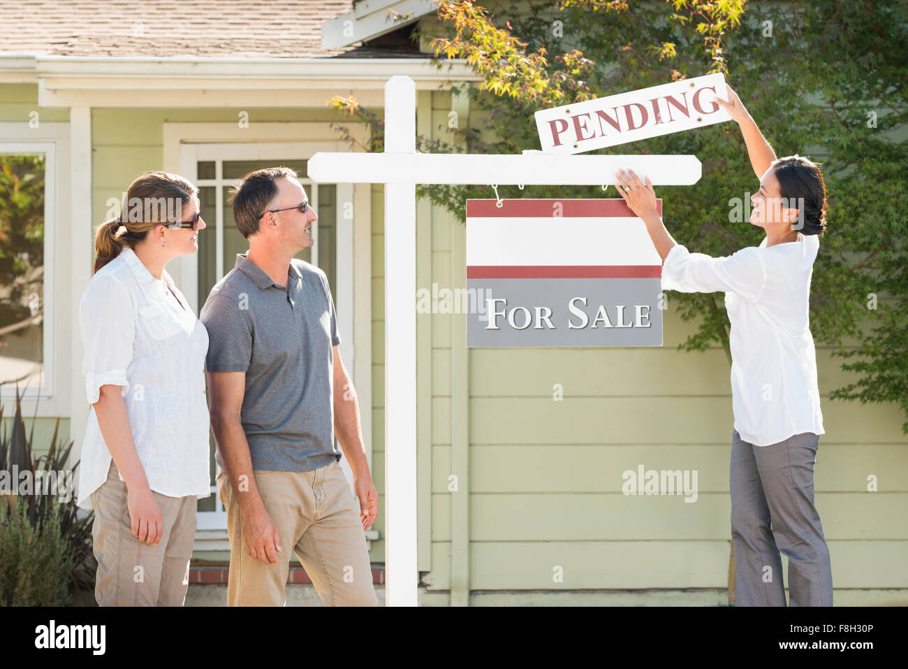 Real estate agent hanging sign outside house Stock Photo