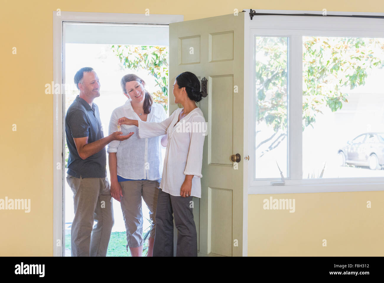 Real estate agent giving couple keys to new home Stock Photo - Alamy