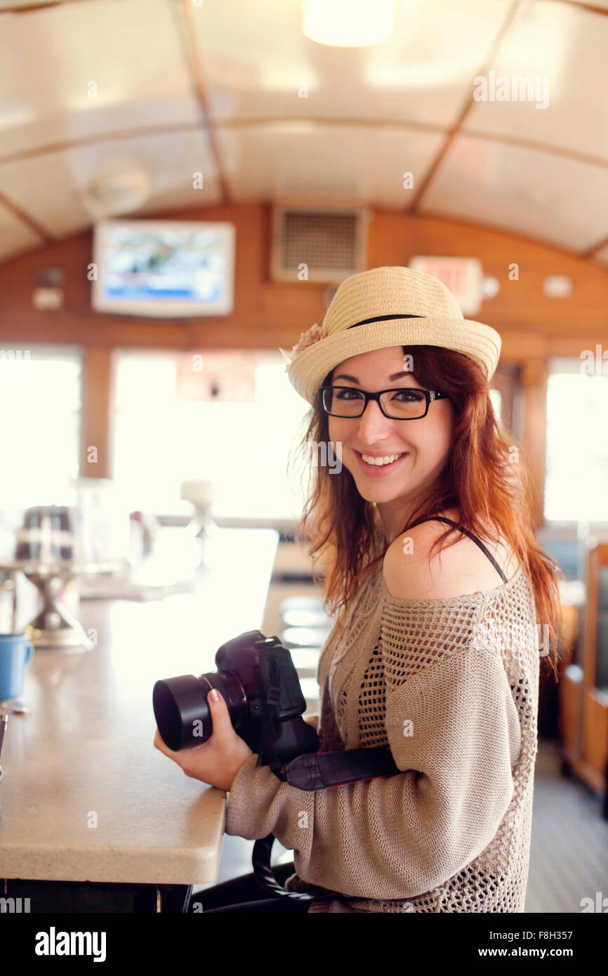 Caucasian woman holding camera in restaurant Stock Photo