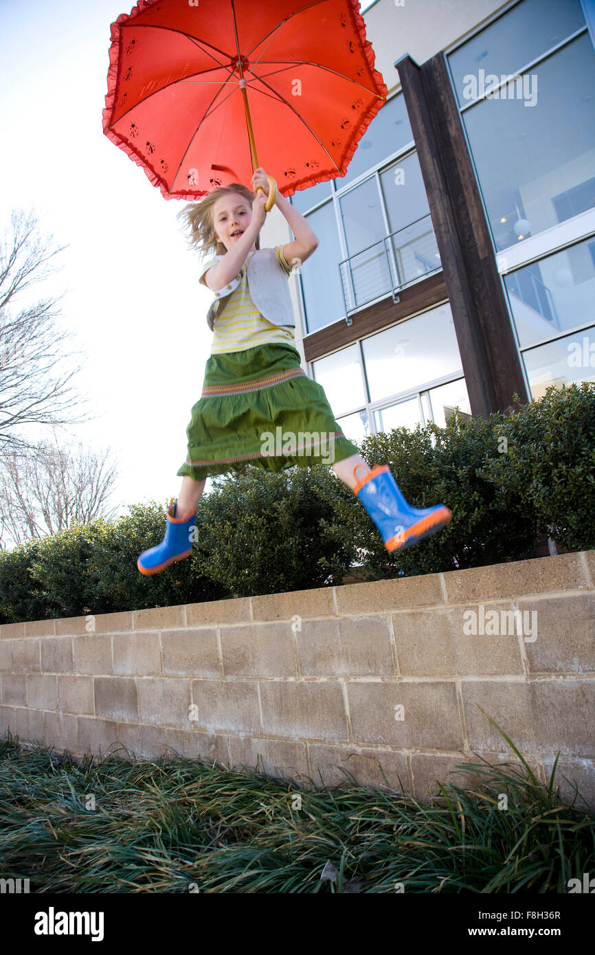 Caucasian girl jumping with umbrella Stock Photo