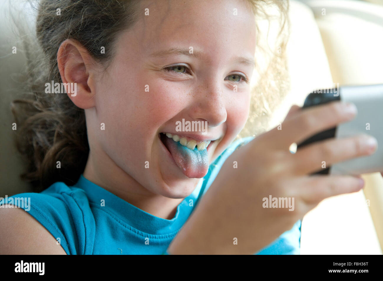 Caucasian girl with blue tongue taking selfie with cell phone Stock Photo