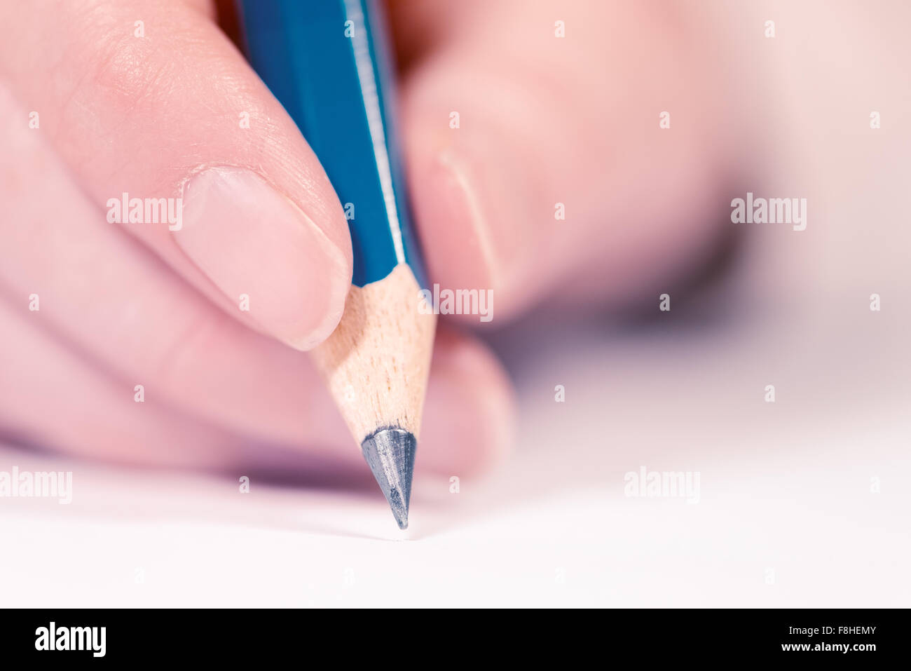 Macro shot of male hand writing notes with pencil on a piece of paper, selective focus Stock Photo