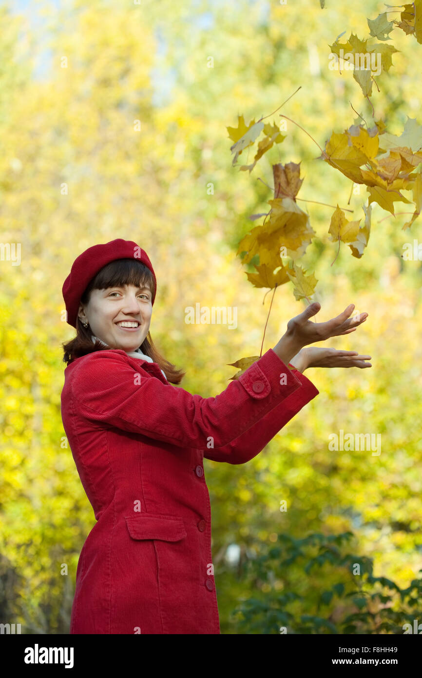 Young woman in red coat throwing yellow maple leaves in autumn Stock ...