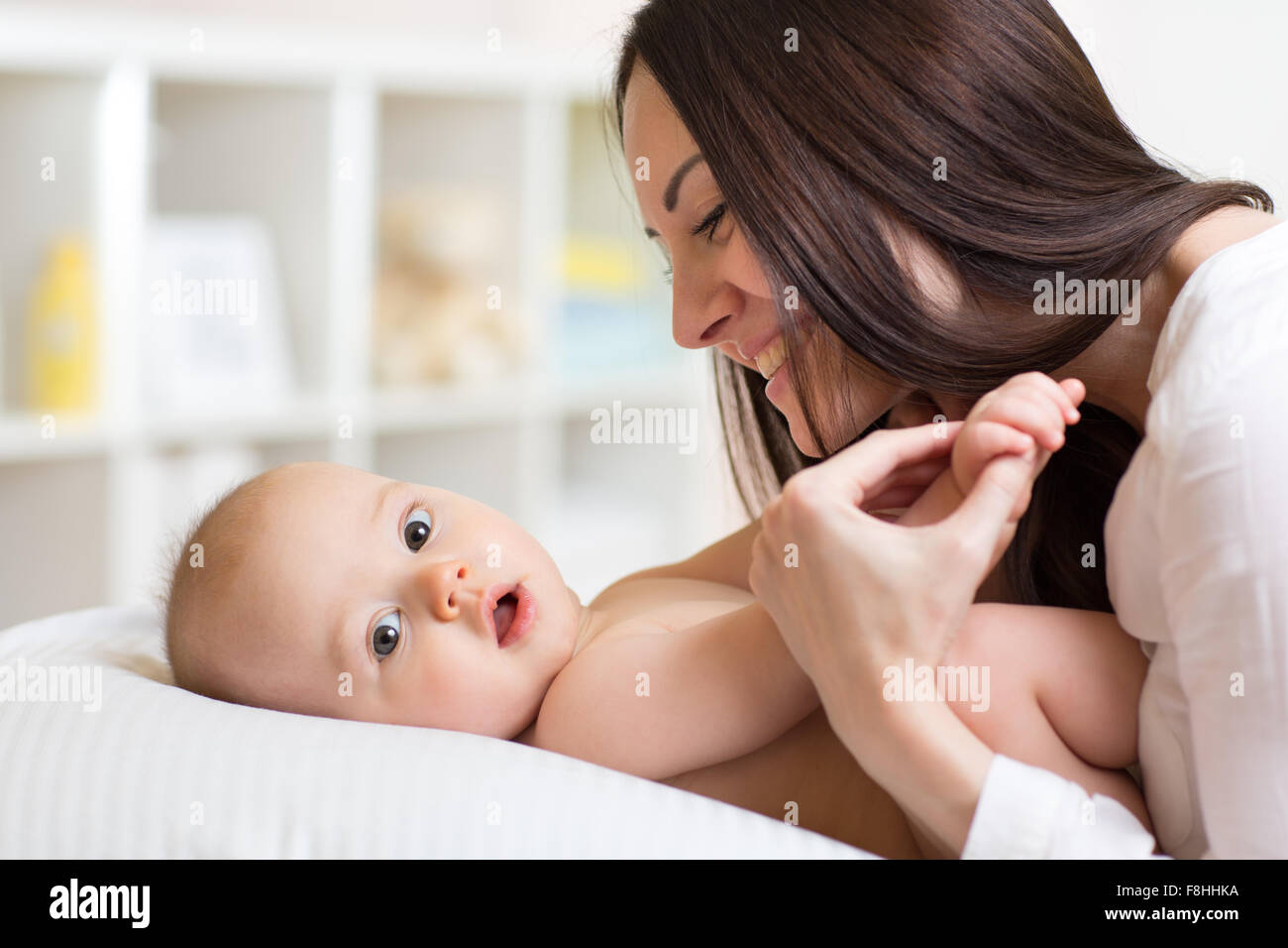 Happy mother playing with baby son in bedroom Stock Photo