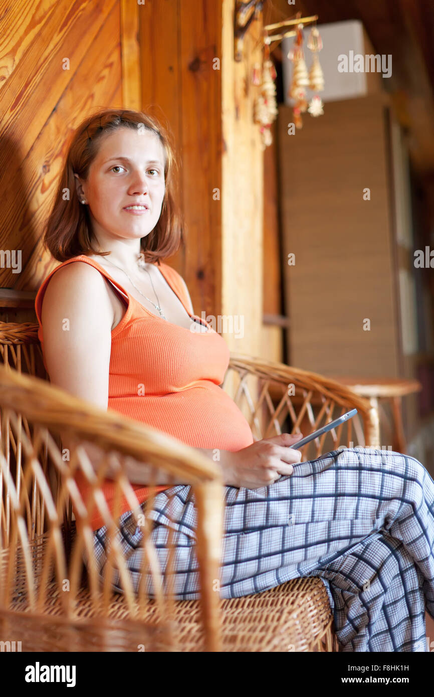 pregnant woman reading e-book in home interior Stock Photo