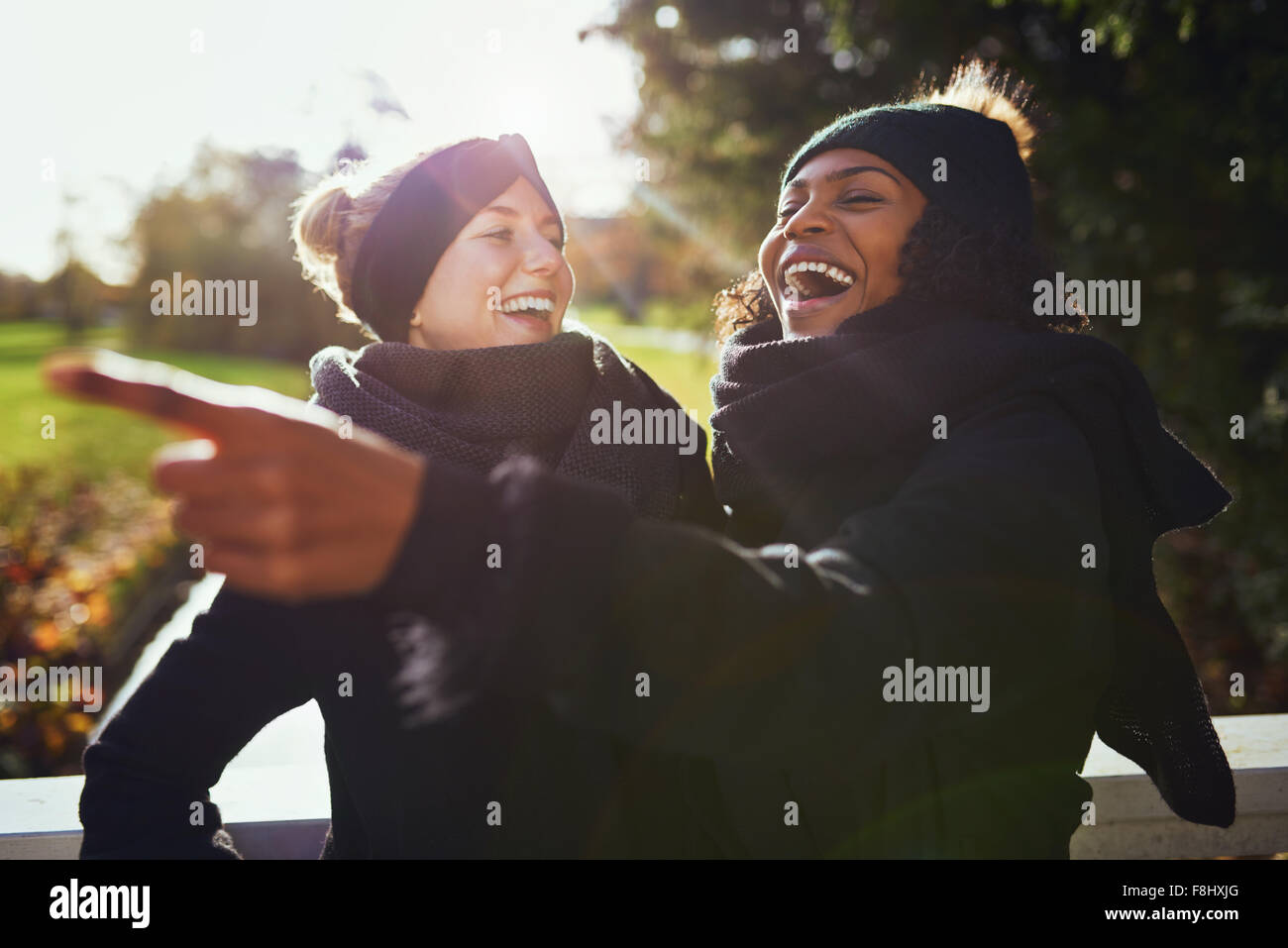 Two women laughing at something while standing in park Stock Photo