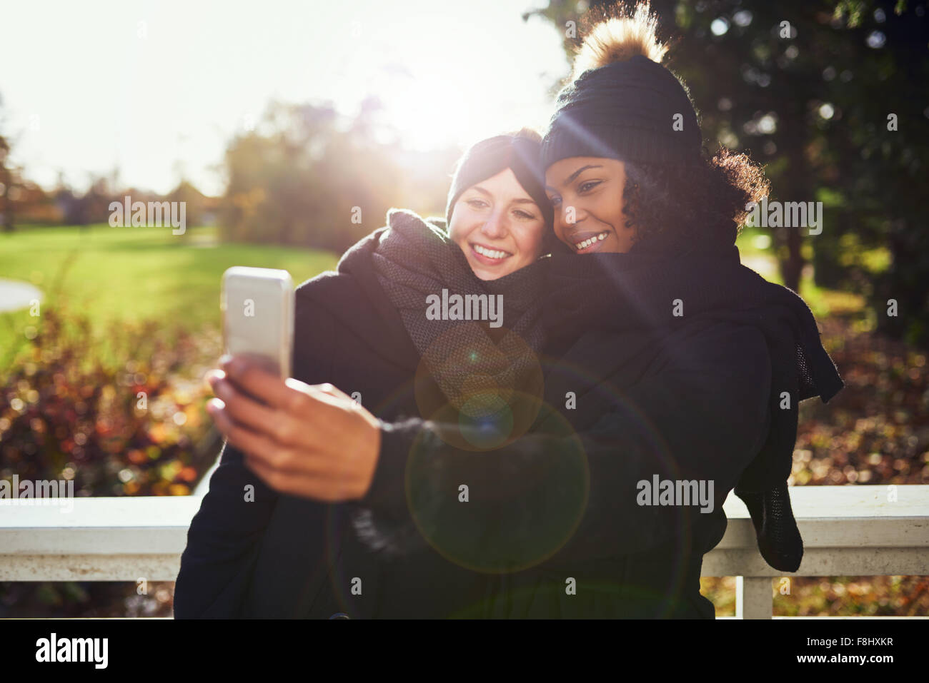 Two smiling young women taking selfie against of autumnal park Stock Photo
