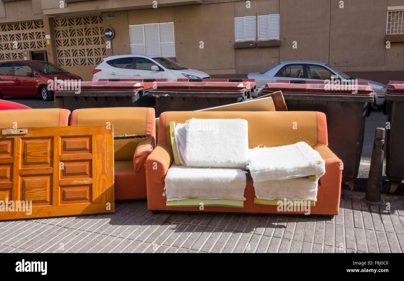Sofa and door left near communial rubbish containers in street in Spain Stock Photo