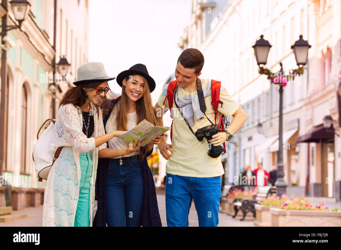 Happy young women and guy with camera as tourists Stock Photo - Alamy