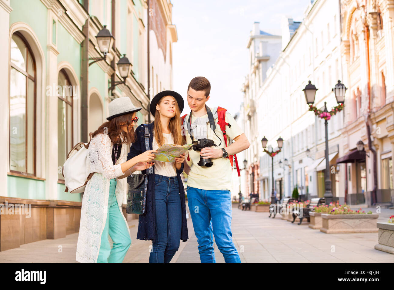 Girls and guy holding camera look at city map Stock Photo
