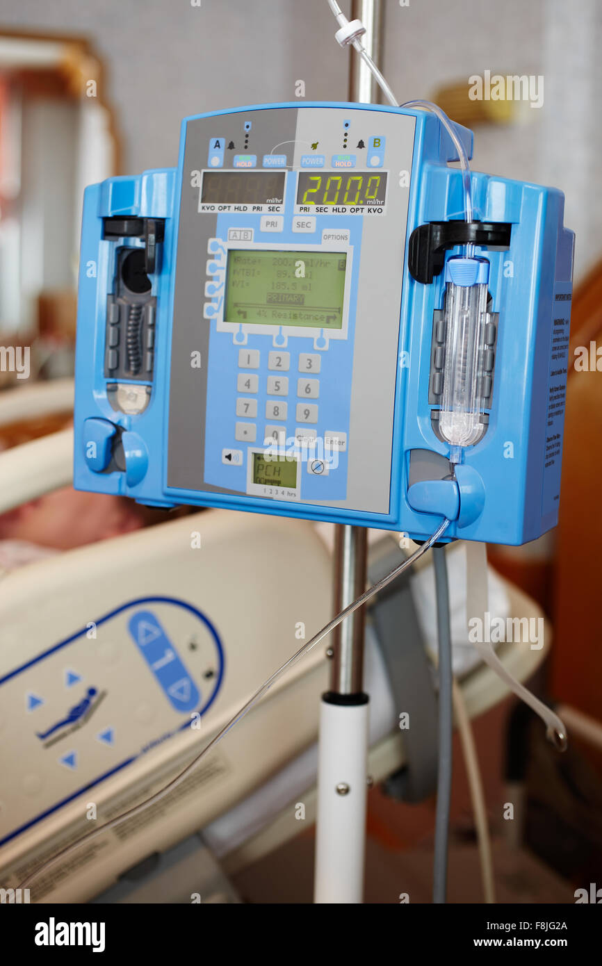 Infusion pump intravenous IV drip next to a bed in a hospital room