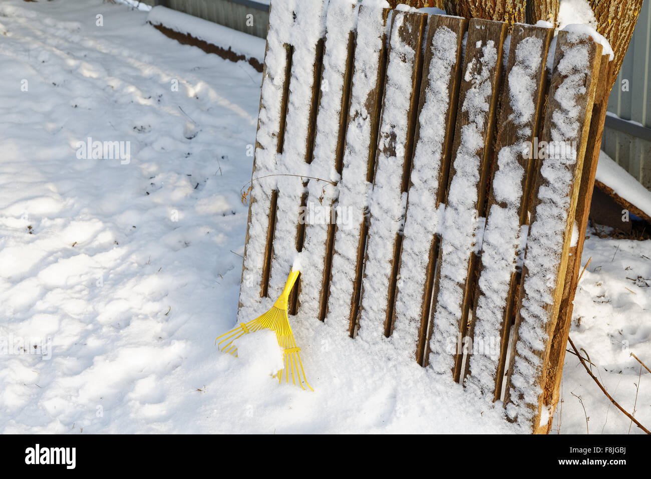 Yellow rake under snow in winter day Stock Photo - Alamy
