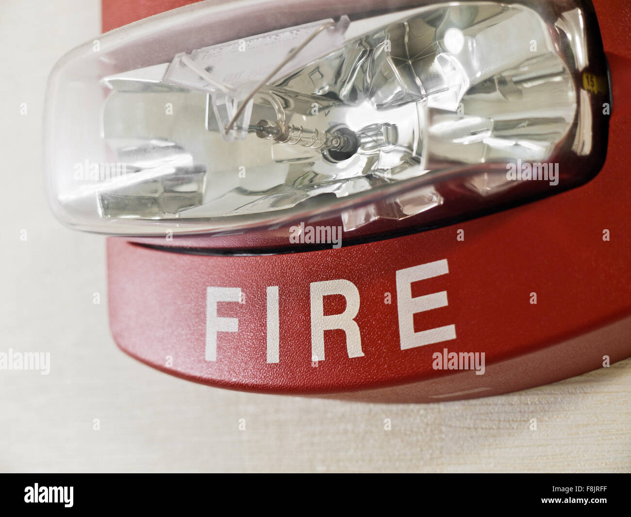 Red fire alarm smoke detector with strobe light mounted on a wall as part of a fire protection system. Stock Photo