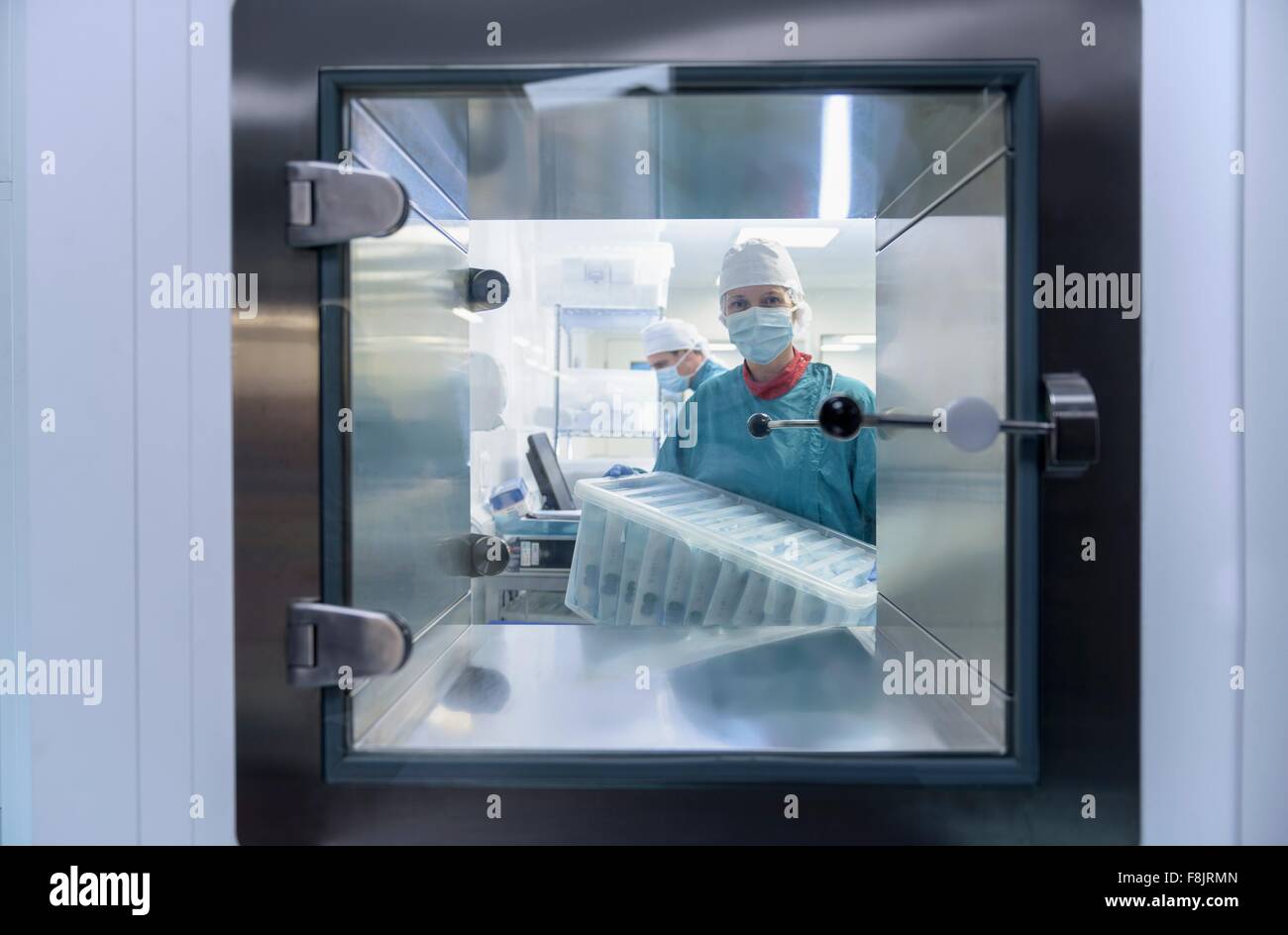 Worker putting surgical instruments into air lock in clean room of surgical instruments factory
