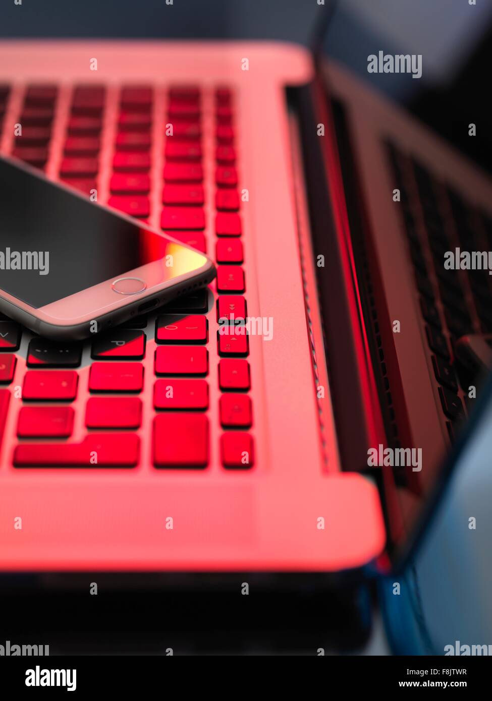 Red light on laptop and mobile phone illustrating danger from hackers Stock Photo