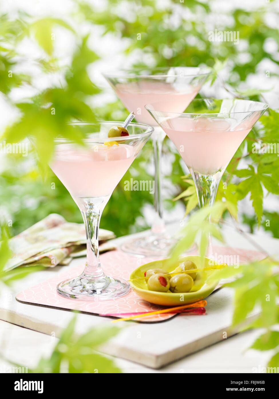 Three glasses of pink grapefruit and martini cocktails with green olives Stock Photo