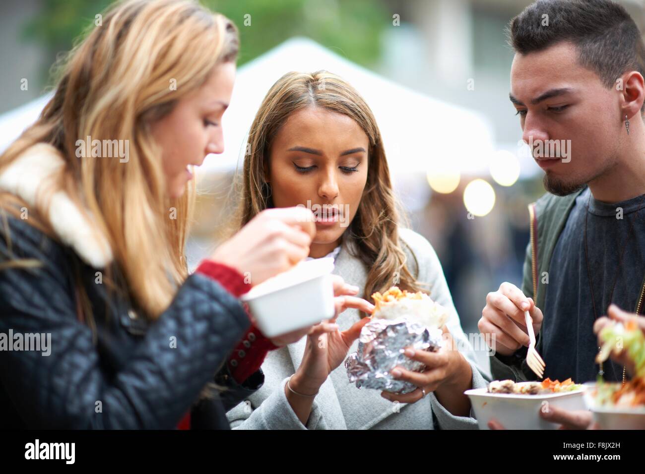 Group of young adults eating takeaway food, outdoors Stock Photo