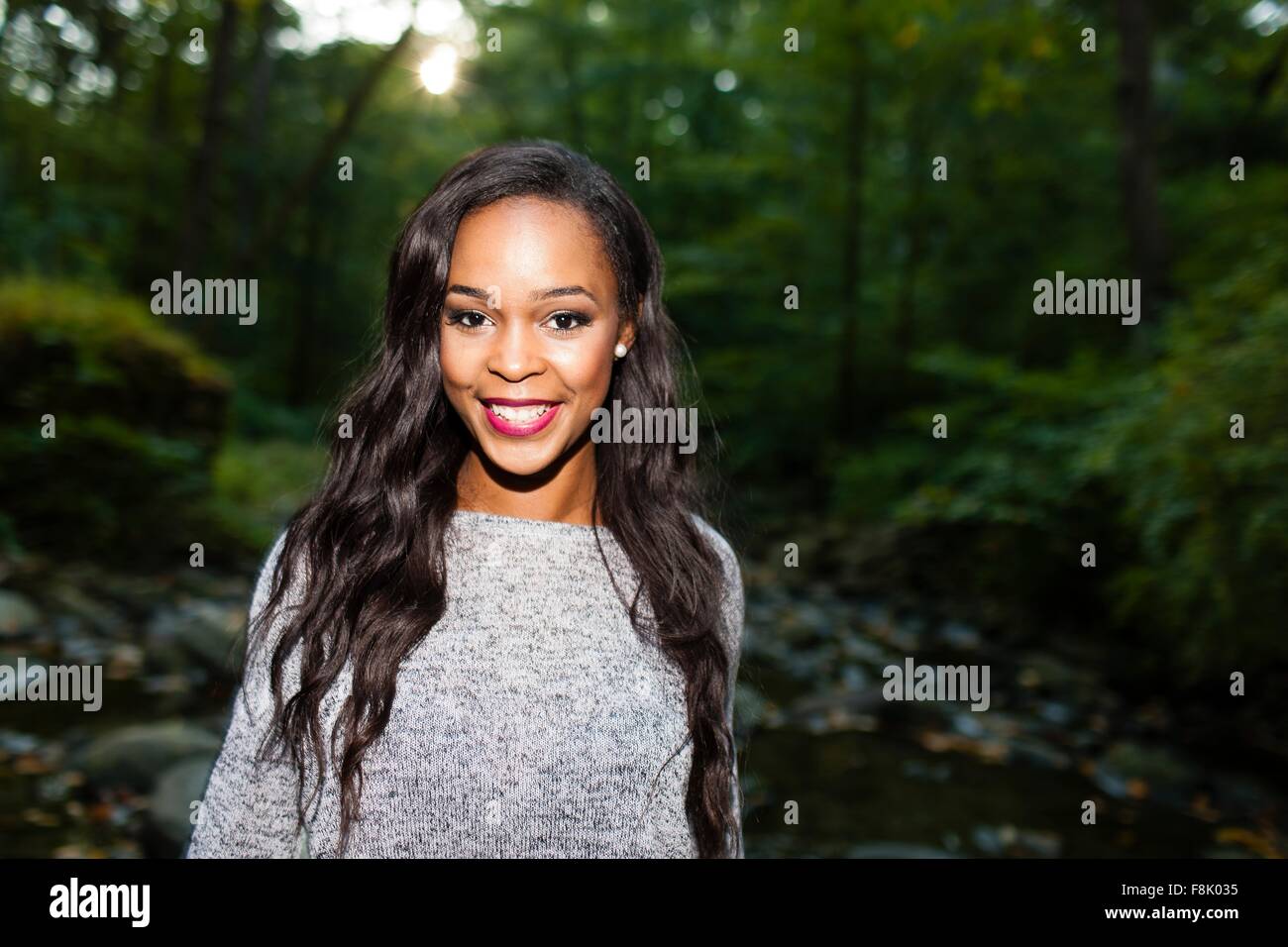 Portrait of happy young woman in darkened forest Stock Photo