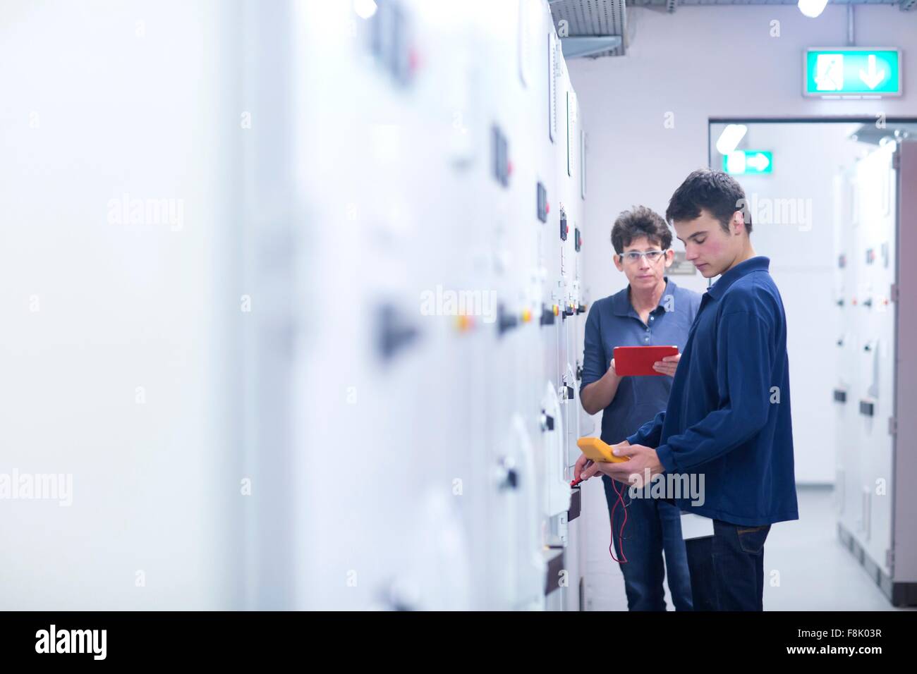 Collegues in control room testing switchgear with electricity meter ...