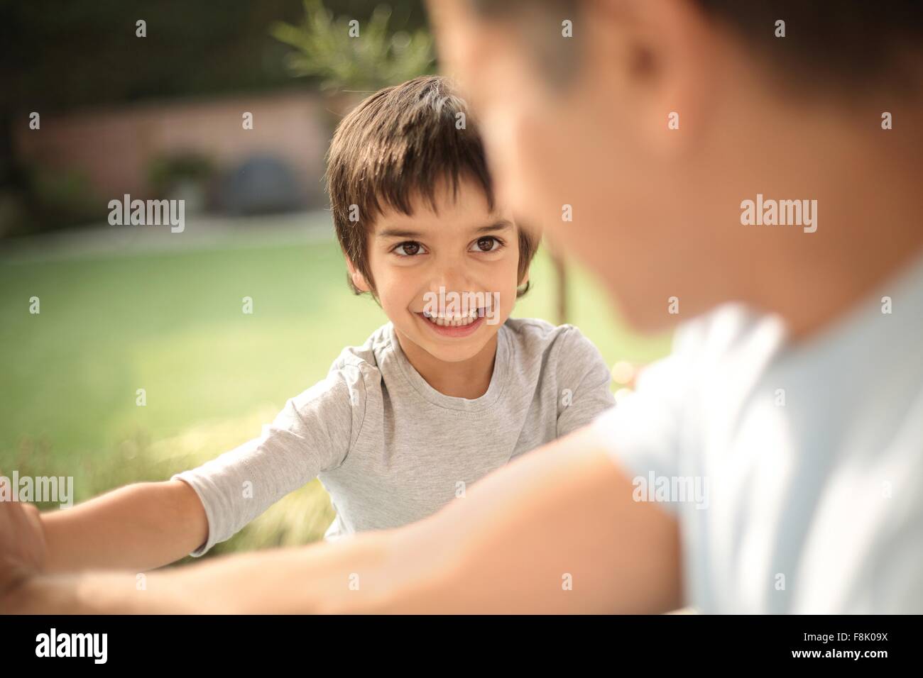 Boy in garden smiling at father, differential focus Stock Photo