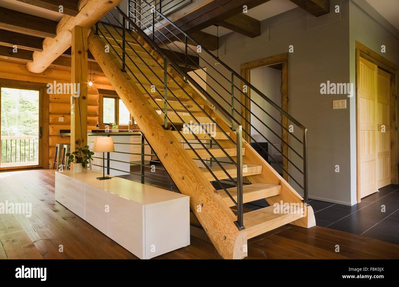 Wood stairway with wrought iron railings in modern Eastern white pine log cabin Stock Photo