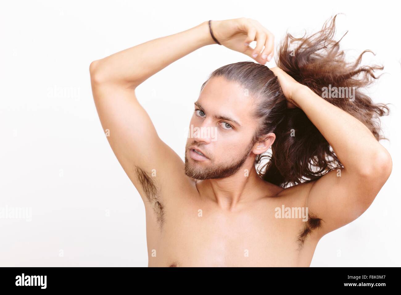 Young Man With Long Hair Putting Hair In Ponytail Stock Photo