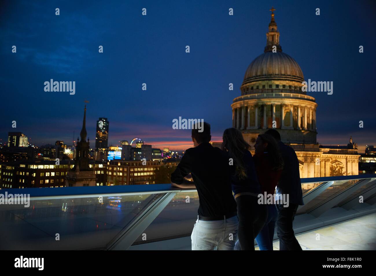 Silhouetted rear view of two young couples looking out to St Pauls at night, London, UK Stock Photo