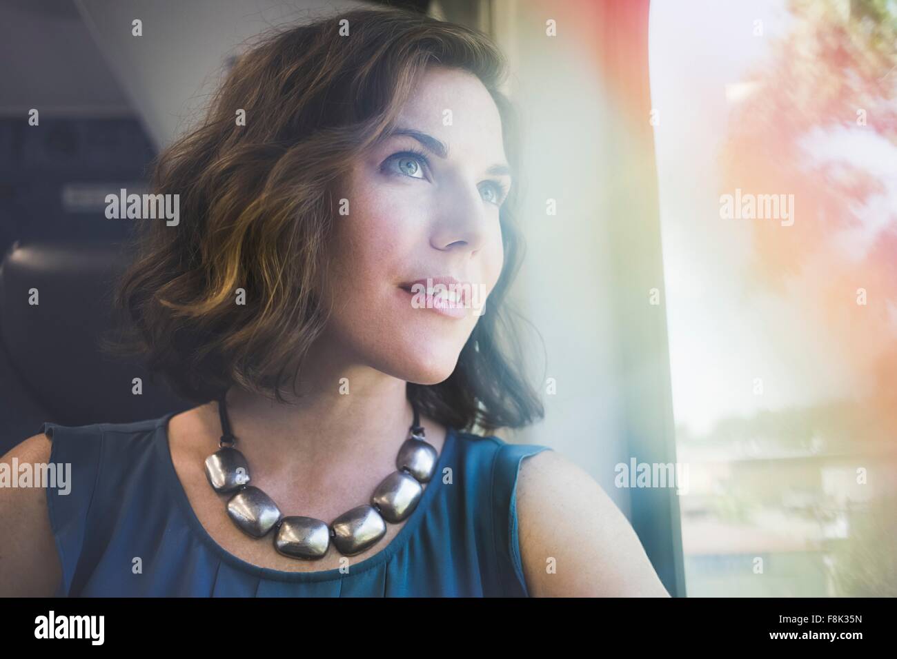 Mid adult woman on train, looking out of window Stock Photo