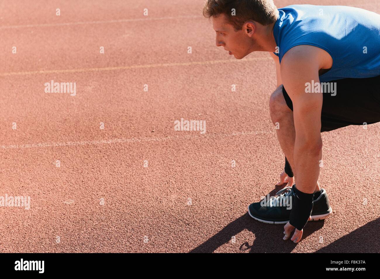 Young man in starting position on sports track Stock Photo