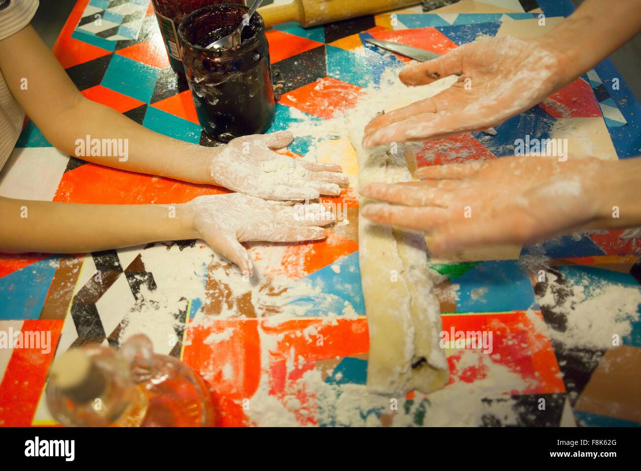 Woman and son comparing messy floured hands at kitchen table Stock Photo