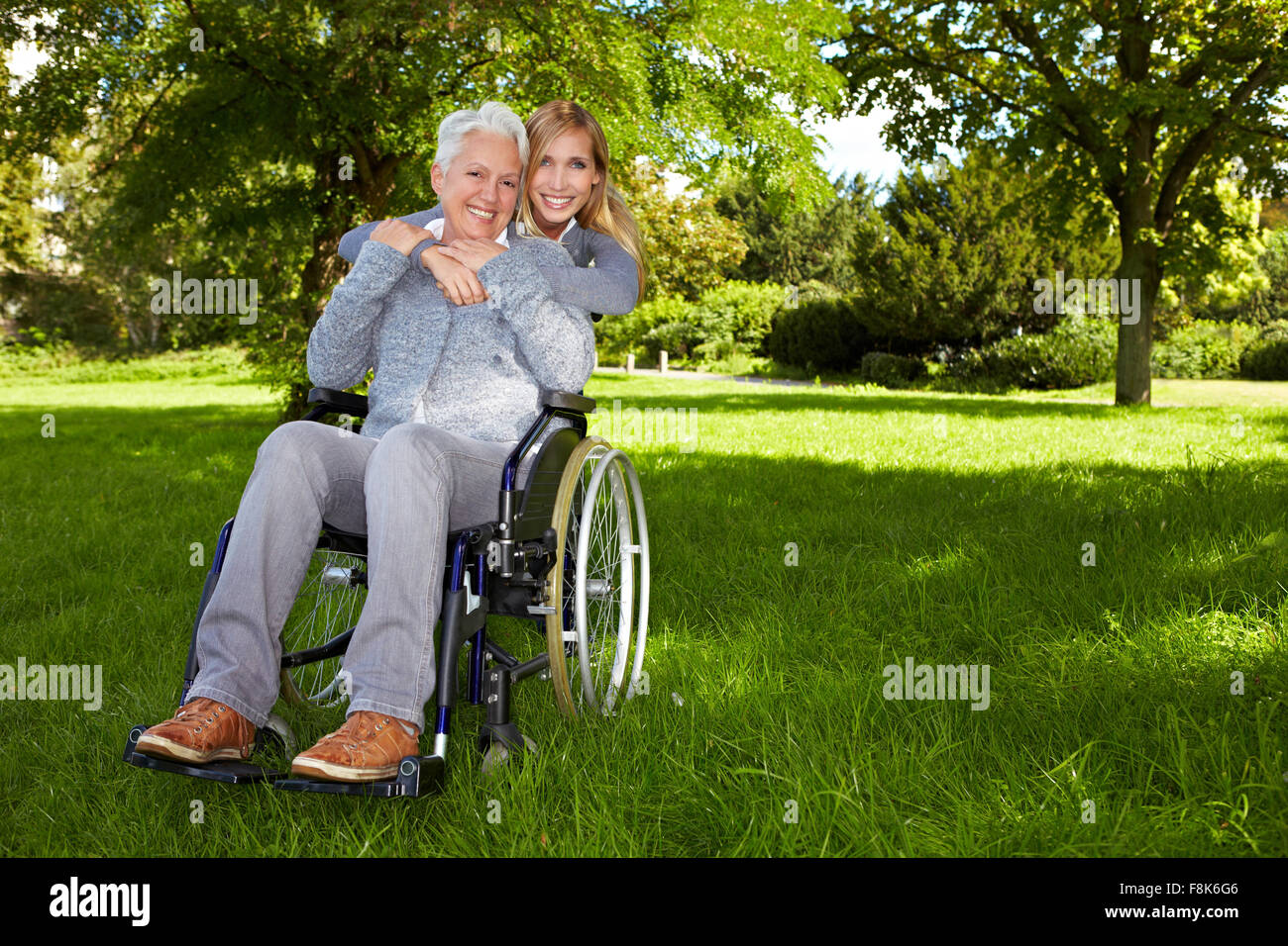 Happy woman in wheelchair with young woman in nature Stock Photo - Alamy
