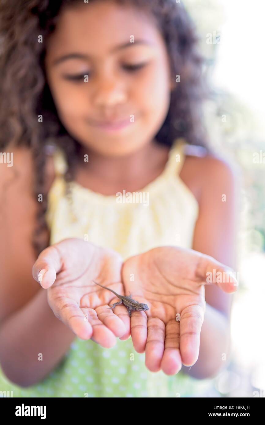 Girl holding small reptile on palm of hands, focus on foreground Stock Photo
