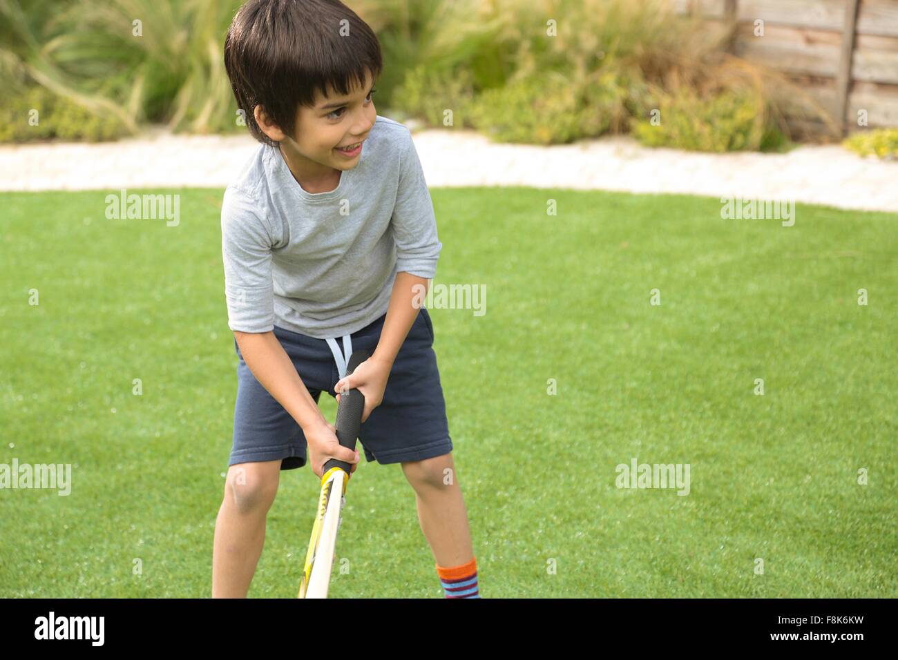 Front view of boy in garden playing cricket looking away smiling Stock Photo