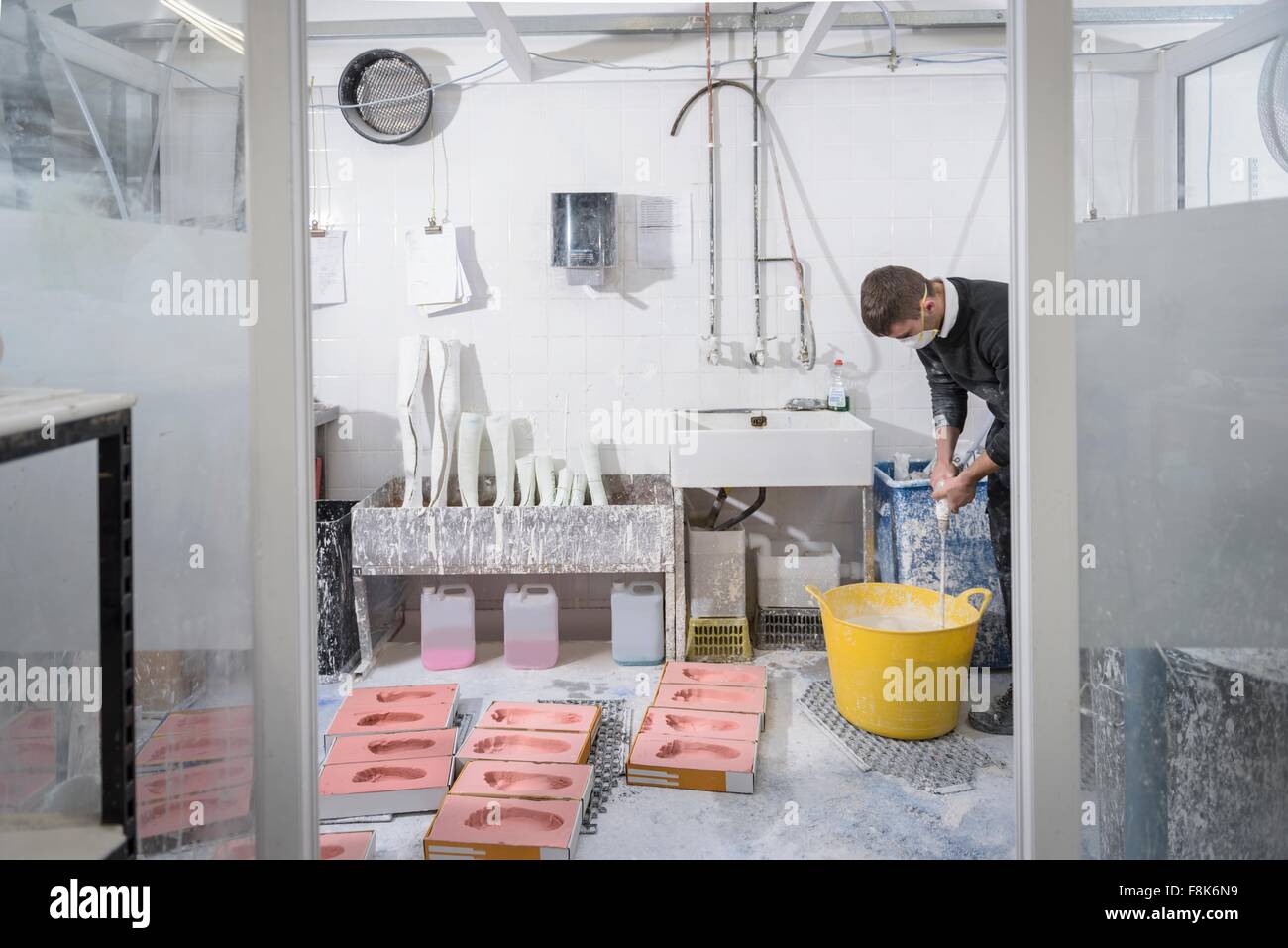Worker casting plaster into foot moulds for orthopaedic support in factory Stock Photo
