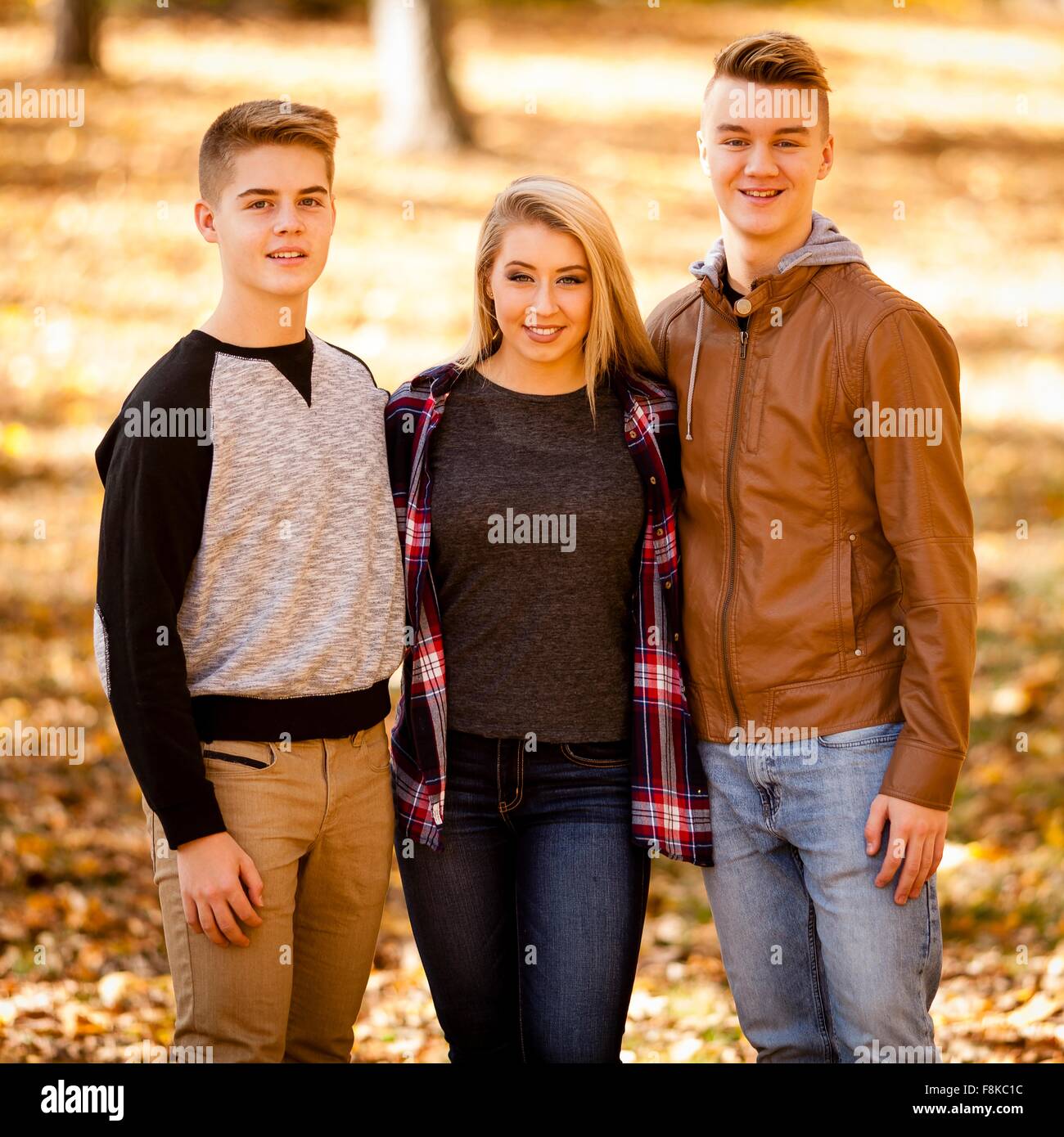 Portrait of young woman and two teenage brothers in autumn forest Stock Photo