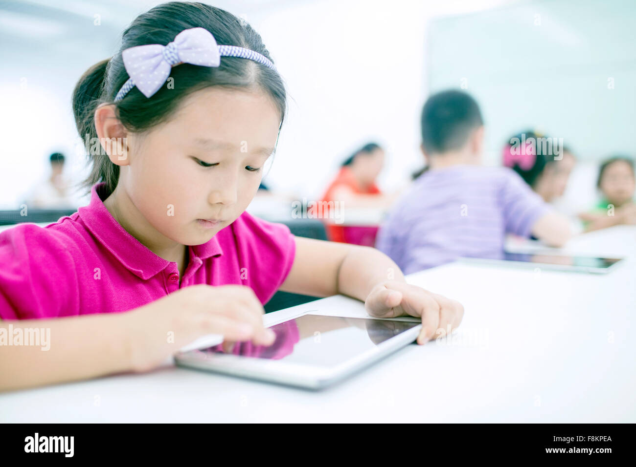 Girl sitting with boy using digital tablet in classroom Stock Photo