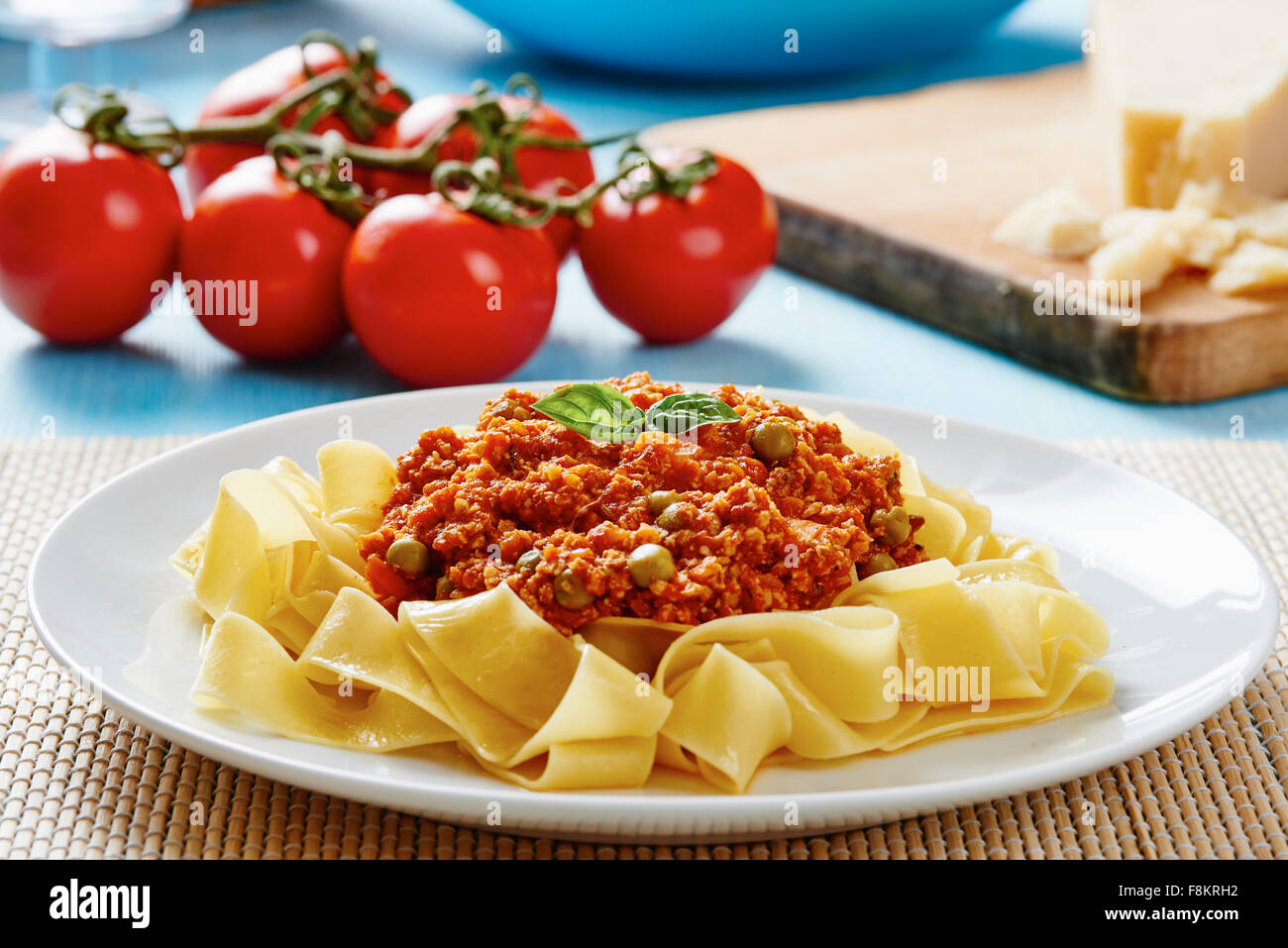 Tagliatelle with Bolognese sauce on white plate and blue wooden table Stock Photo