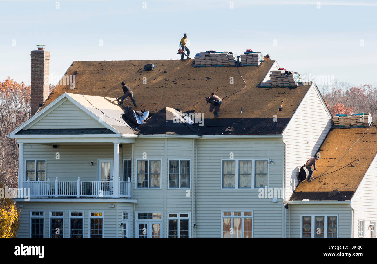 Workmen on roof of an American home removing the old shingles and felt ready to replace the roof, USA Stock Photo