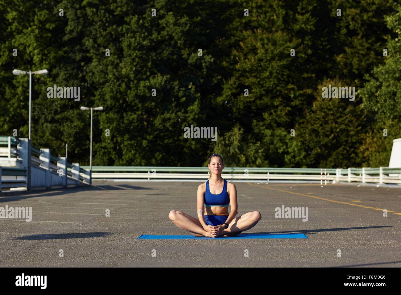 Young woman practicing yoga lotus pose in urban parking lot Stock Photo ...