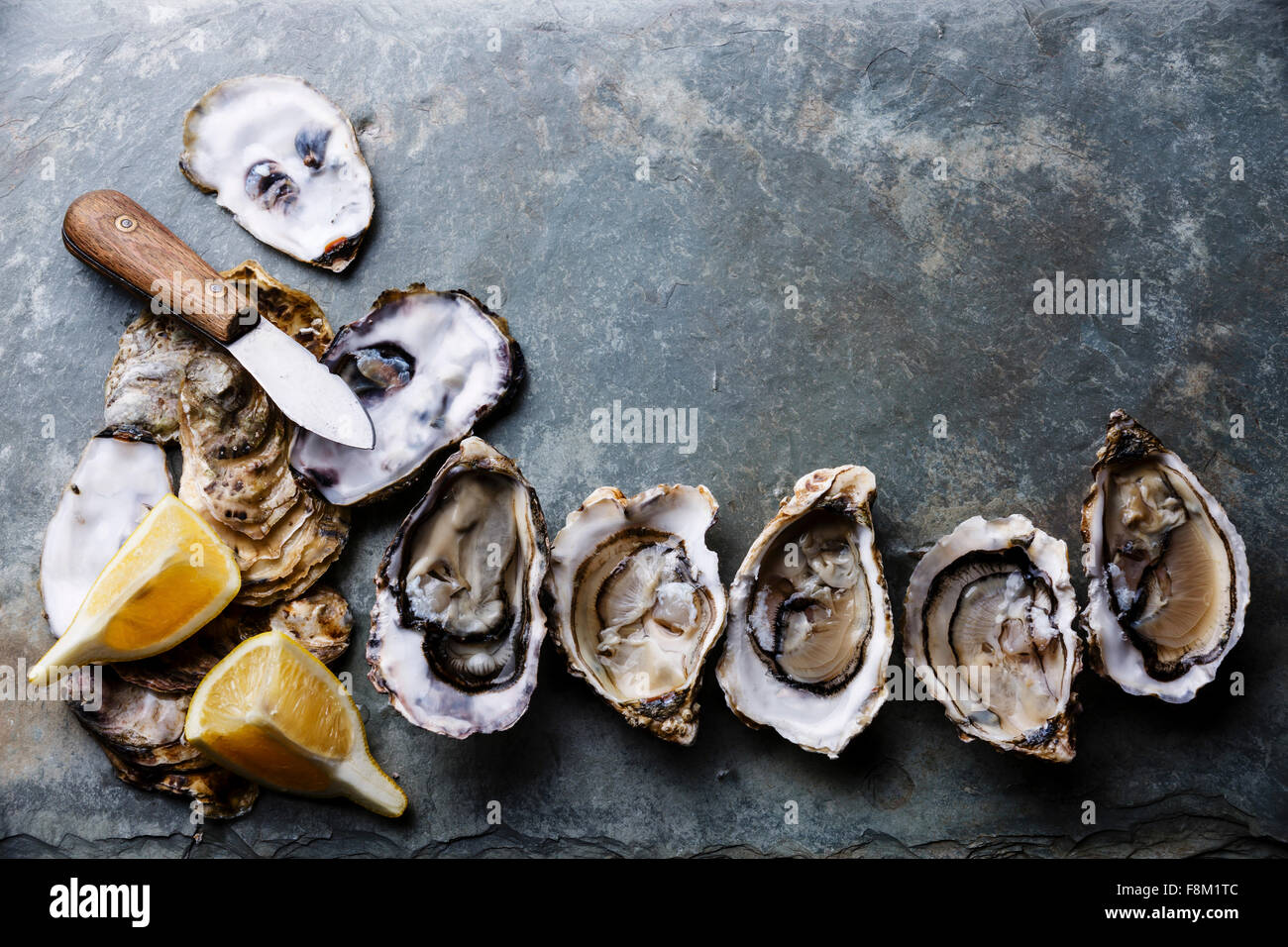 Open Oysters Fines de Claire on stone plate with lemon Stock Photo