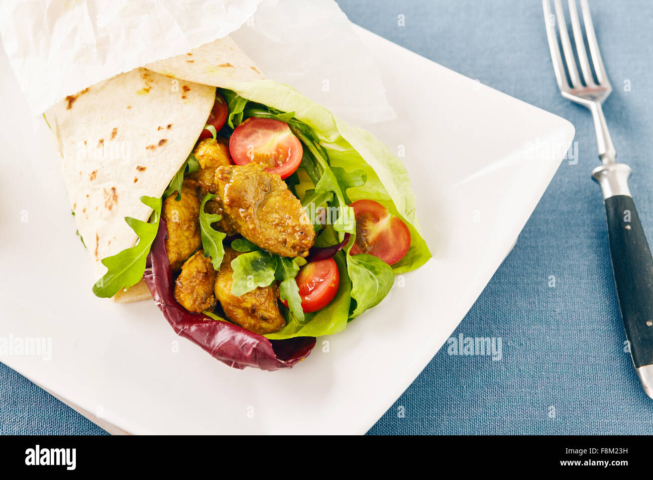 pork wraps on a white serving plate with rocket and lettuce, pastel colors Stock Photo