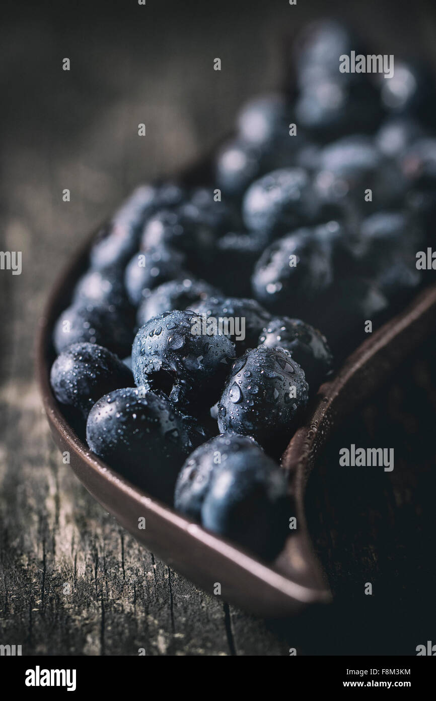 Close up of fresh wet blueberries in decorative ceramic plate over old wooden table. With retro filter effect Stock Photo