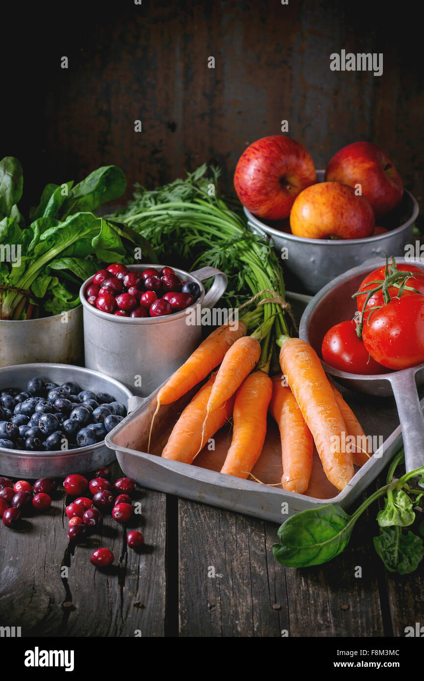 Assortment of fresh fruits, vegetables and berries. Bunch of carrots, spinach, tomatoes and red apples, blueberries and cranberr Stock Photo